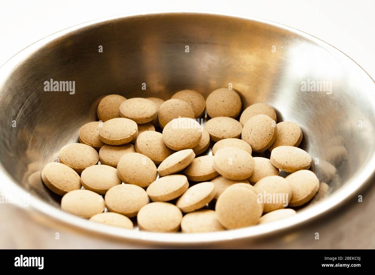 Cats and dogs vitamin supplement in metal bowl on white background. Pet health concept Stock Photo