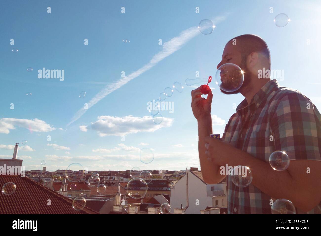 Man blowing soap bubbles from his balcony. Exit restriction quarantine due to coronavirus, home office and social media concept Stock Photo