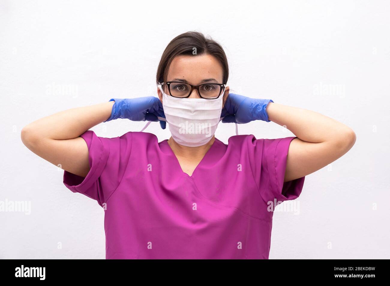 Attractive Female Doctor or Nurse Putting on Protective Face Mask. Stock Photo