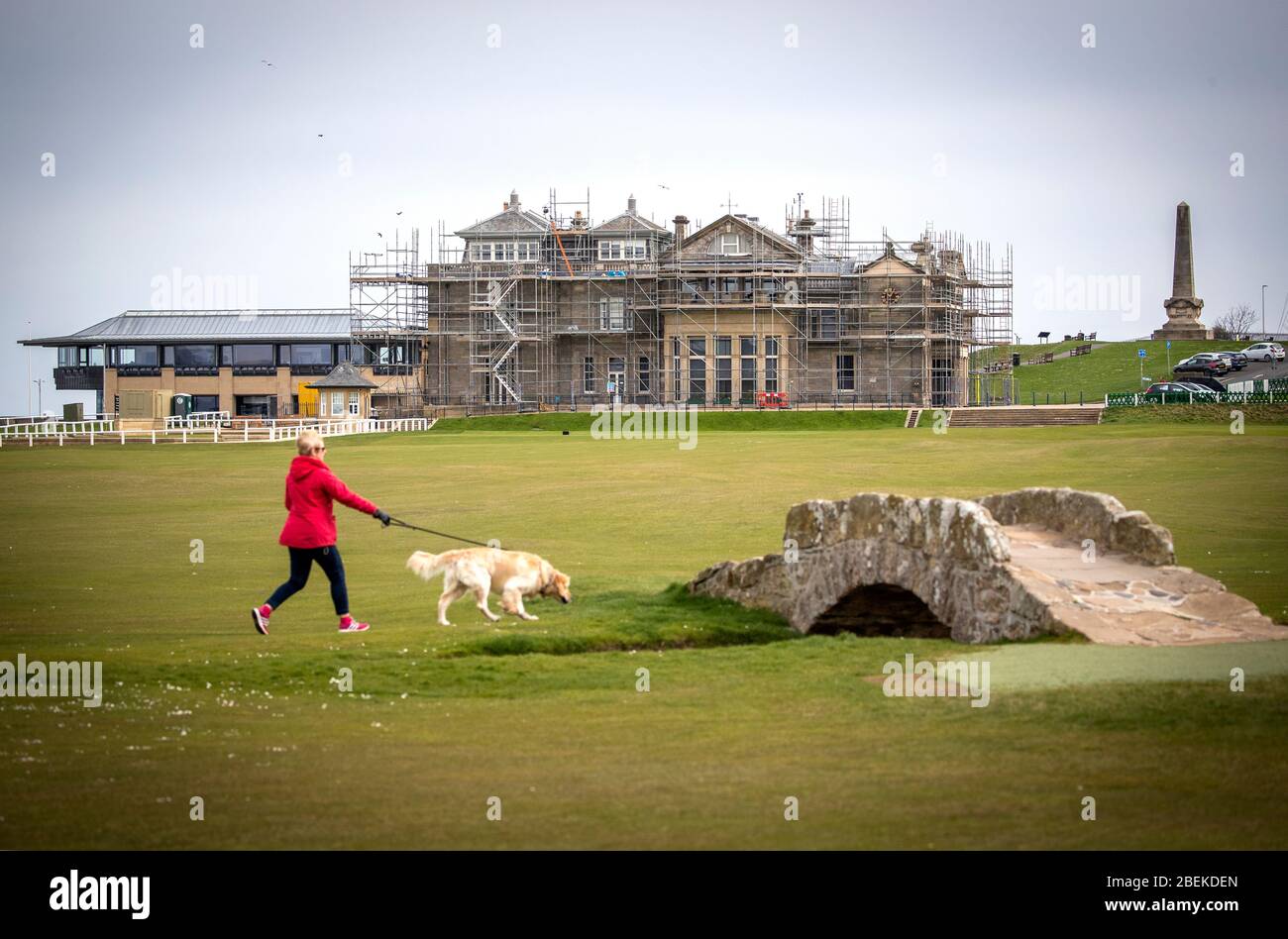 A dog walker passes the Swilcan Bridge on the Old Course at St Andrews in Scotland. Known as the home of golf, the oldest and most iconic golf course in the world will host the 150th Open in 2022 following this years Open at Royal St George's in Kent being postponed until next year. Stock Photo