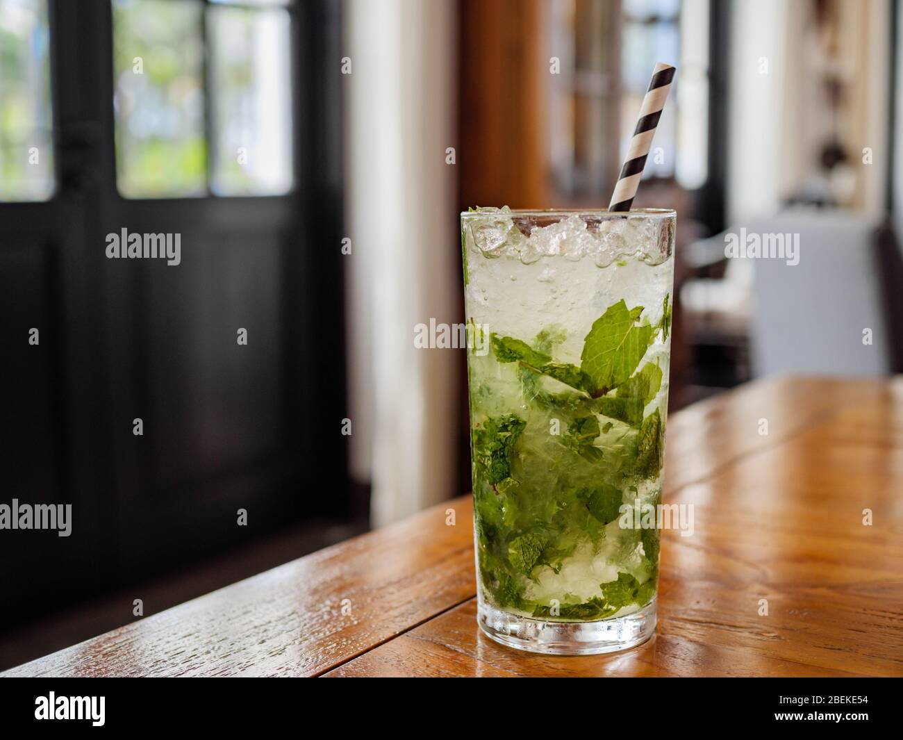 Mojito cocktail with fresh mint leaves and ice cubes in a highball glass during daytime in home / restaurant setting with copy space Stock Photo
