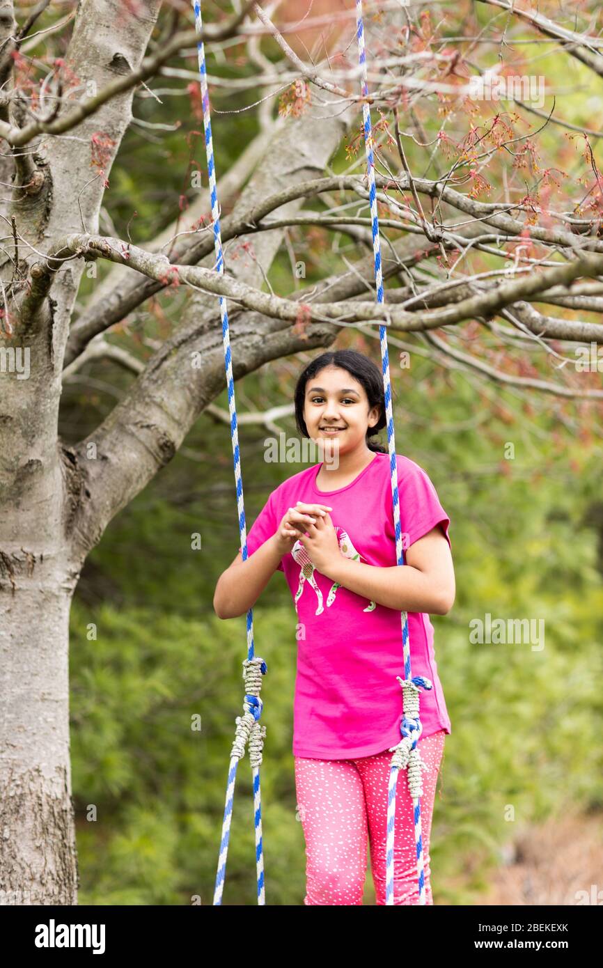 Outdoor Portrait of a Young Girl on a Swing in Spring Stock Photo