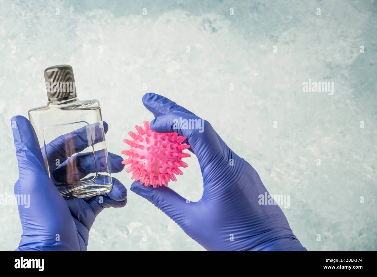 hands in blue disposable surgical gloves holding a bottle of cologne to disinfection the virus Stock Photo