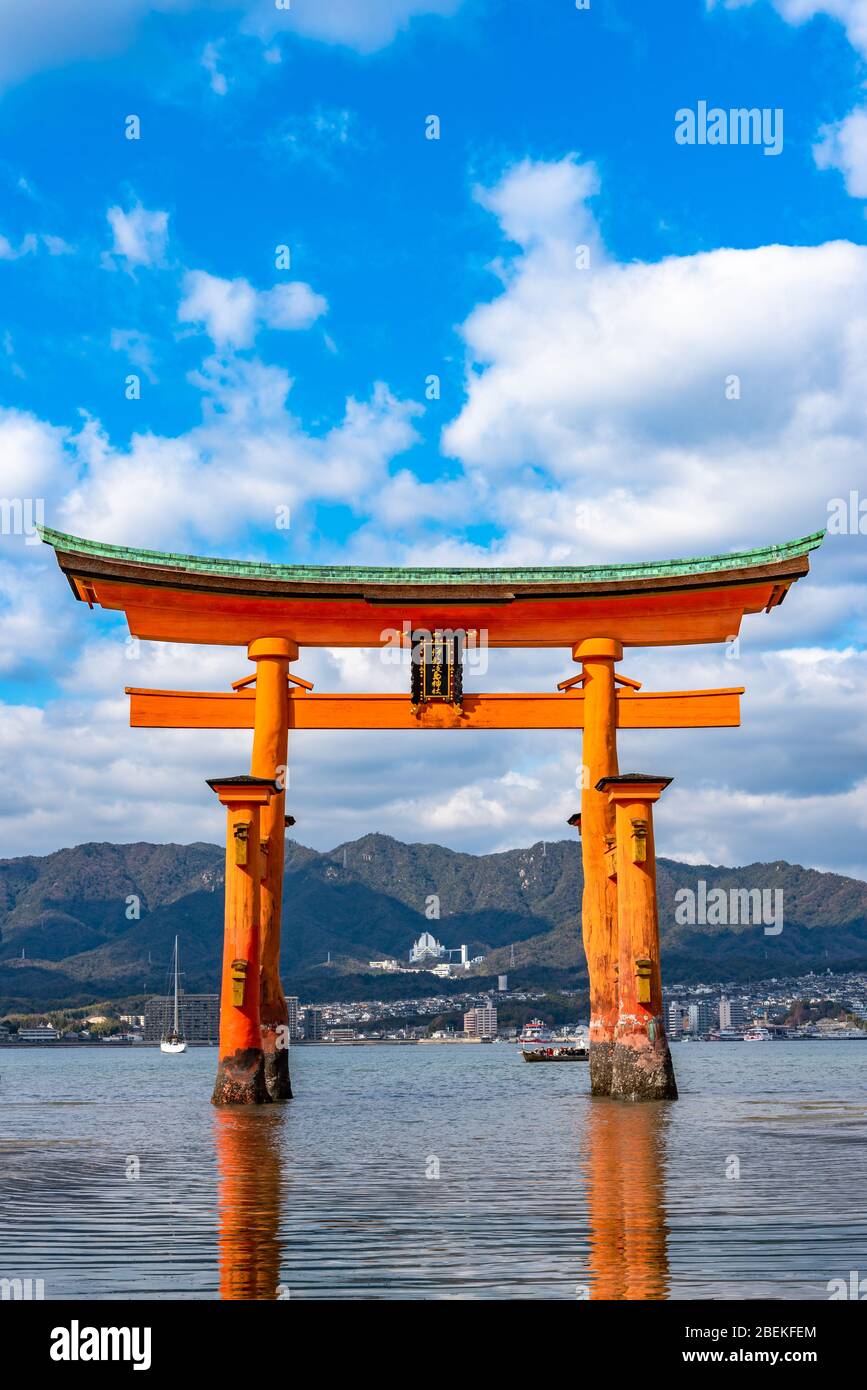 Floating orange red giant Grand O-Torii gate stands in Miyajima island bay beach at low tide in front of Itsukushima Shrine on sunny day. Hiroshima Stock Photo