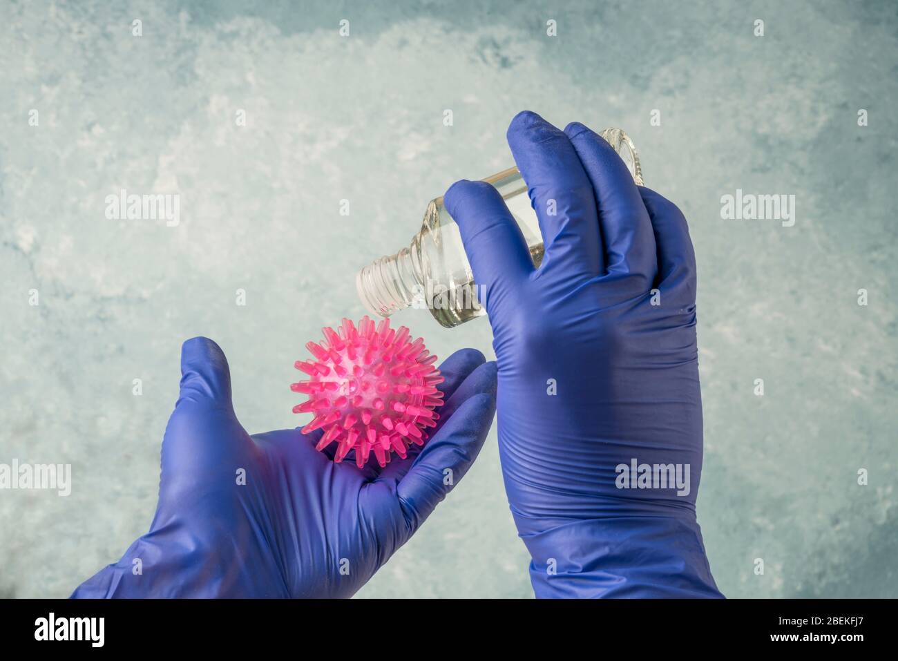 hands in blue disposable latex surgical gloves pouring cologne or alcohol to disinfection the virus Stock Photo