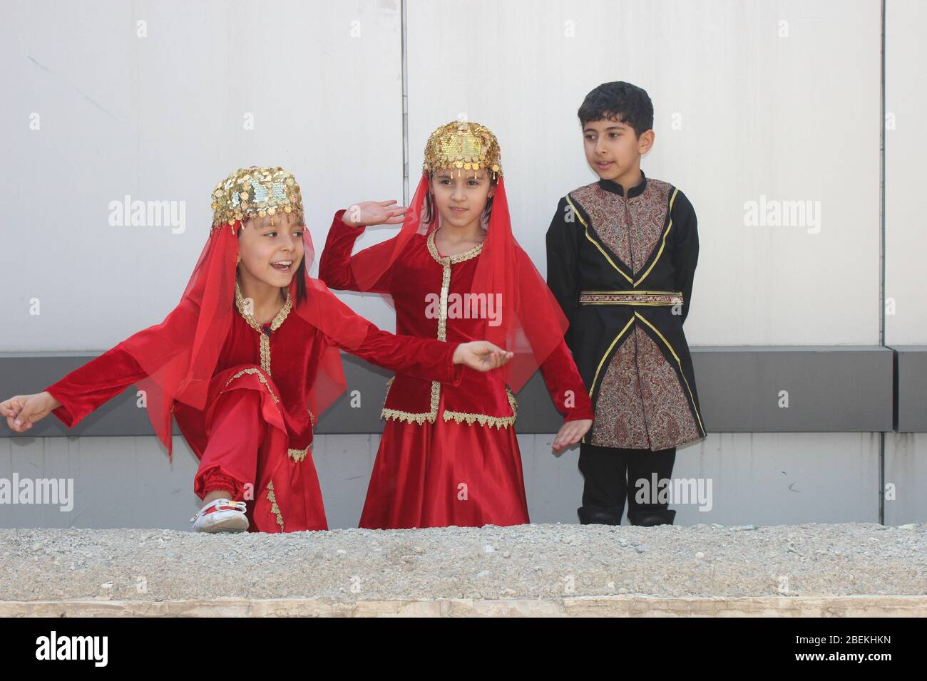 Iranian children in traditional Azeri red clothes, with a smile, at a folklore festival in Iran Stock Photo