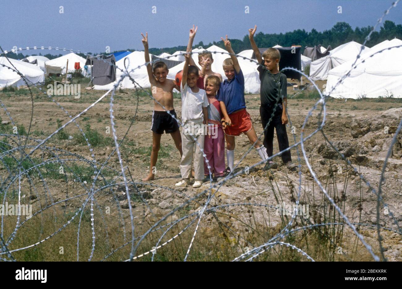 1995 Tuzla, Bosnia -  homeless child refugees give victory salute at Tuzla airfield temporary UN refugee camp for Bosnian Muslims fleeing the Srebrenica Massacre during the Bosnian war Stock Photo