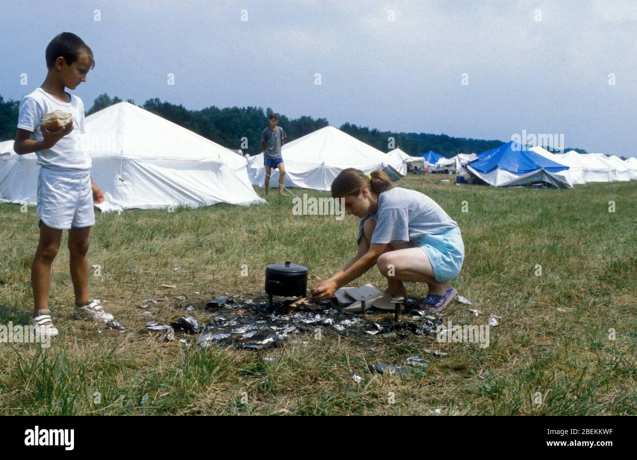 1995 - Tuzla airfield temporary UN refugee camp for Bosnian Muslims fleeing the Srebrenica Massacre during the Bosnian war. Children setting up cooking facilities using wood Stock Photo