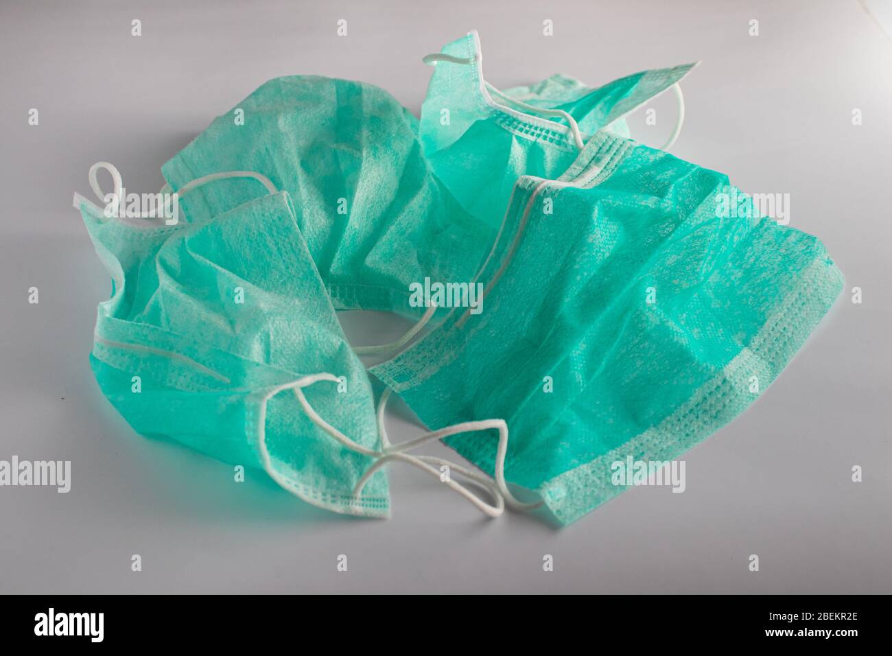 bunch of used green surgical masks on a white background Stock Photo