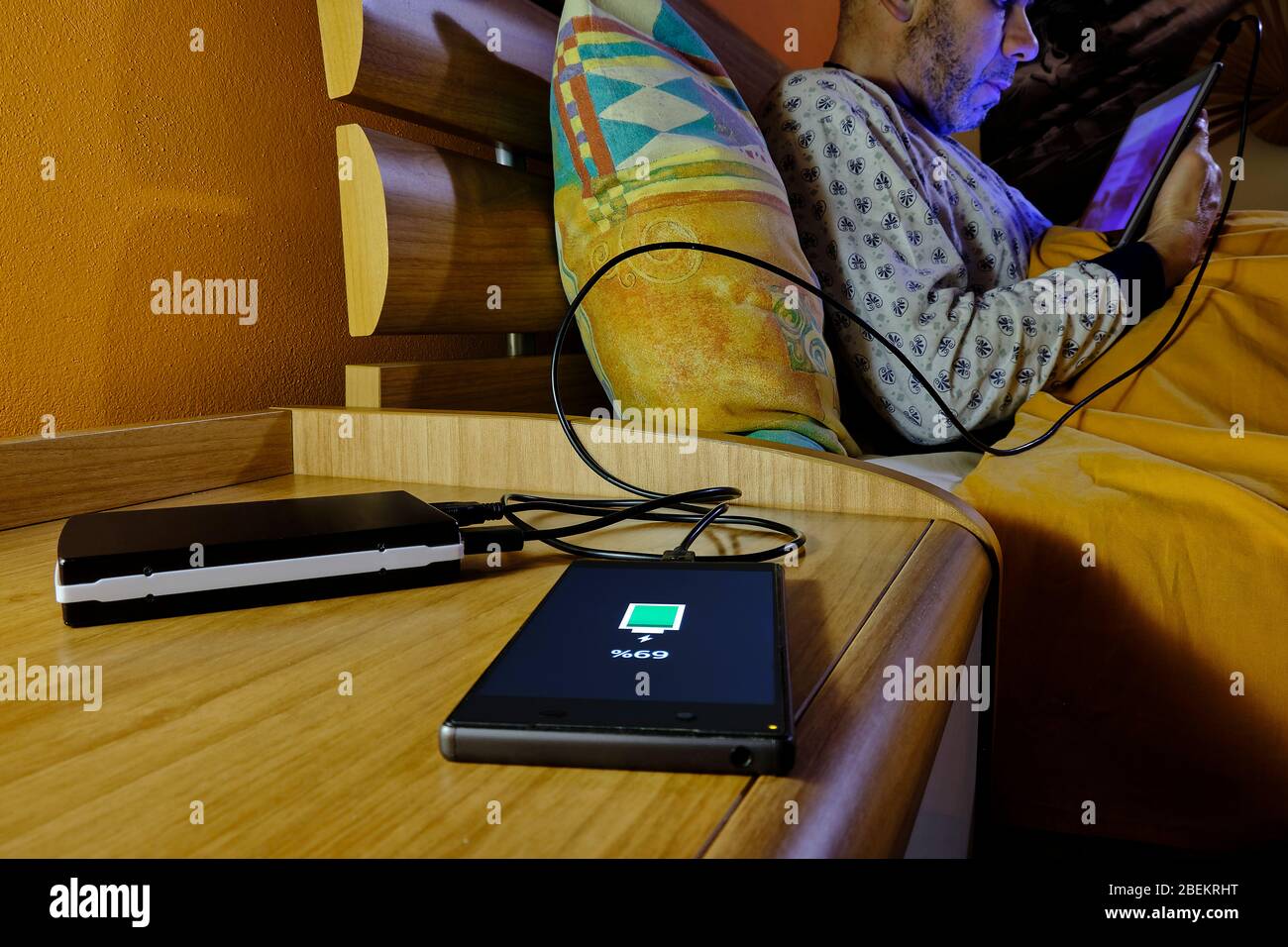 Smartphone in charge with a powerbank on a bedside table Stock Photo