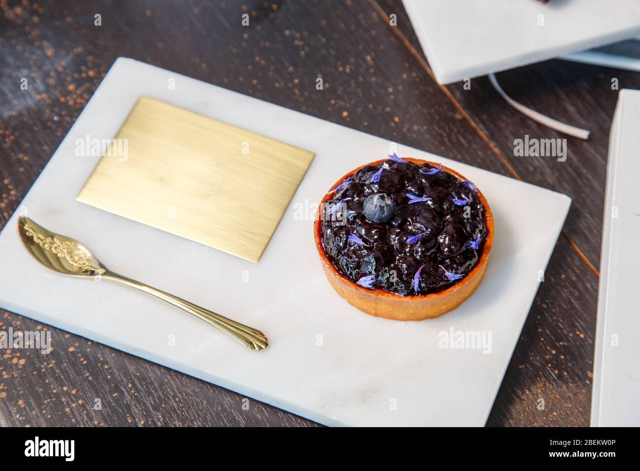 Blueberry pie on a marble plate and golden spoon in a restaurant with copy space. Stock Photo