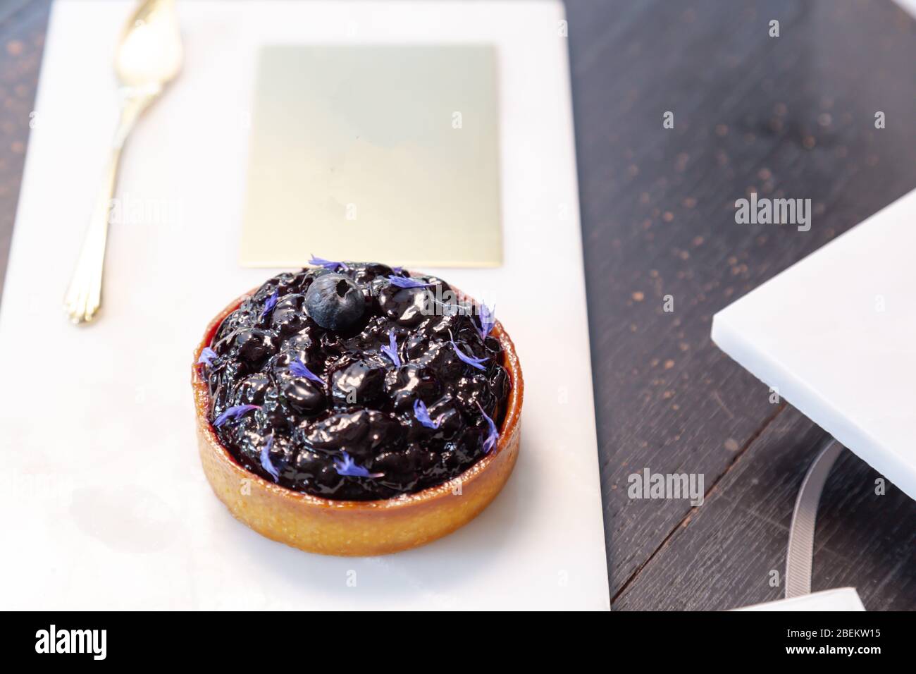 Blueberry pie on a marble plate and golden spoon in a restaurant with copy space. Stock Photo
