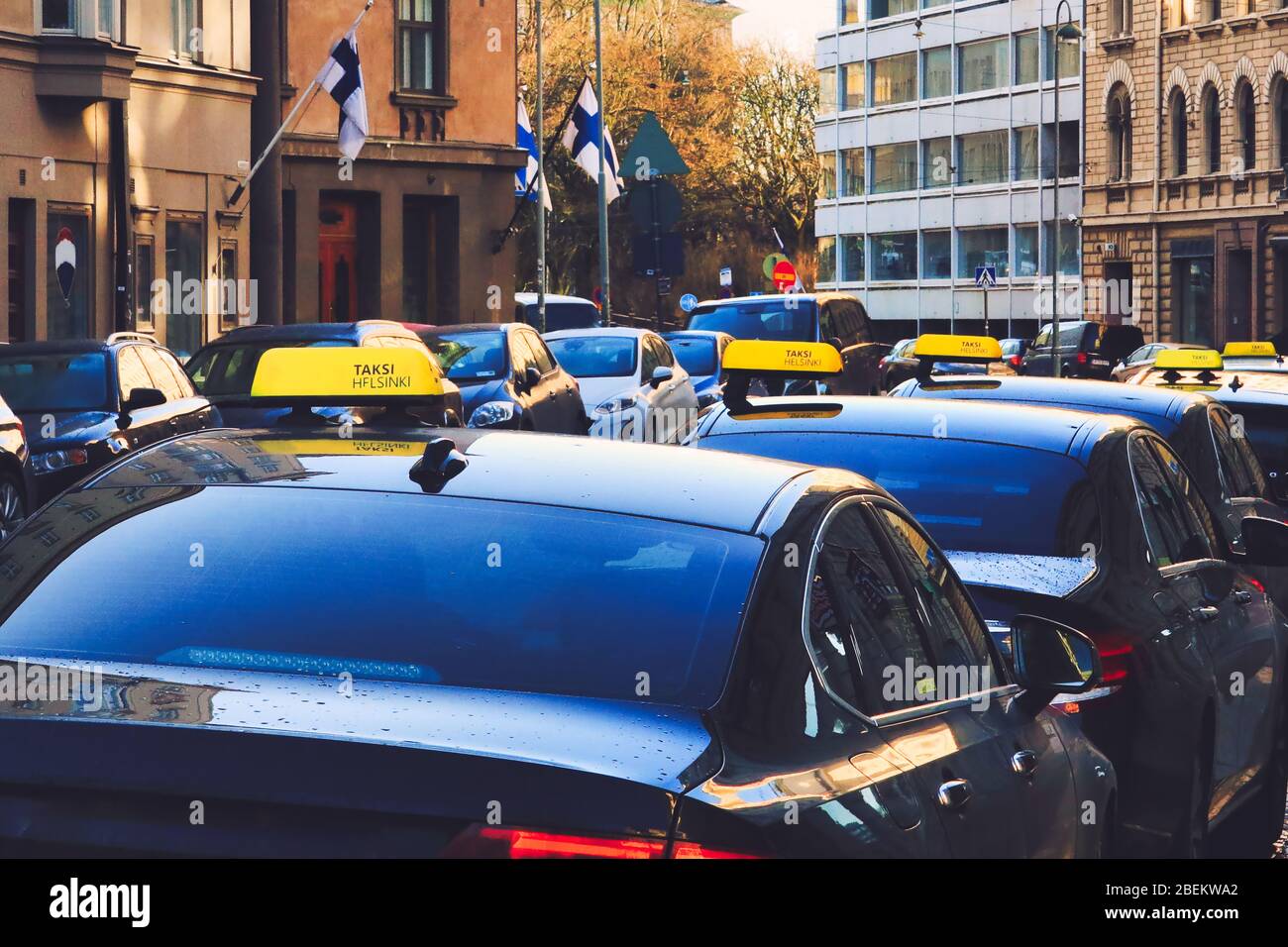 Taxi cab line up by street in Helsinki, Finland. Image contains intentional grain from artistic filters. Identifiable elements removed. Stock Photo