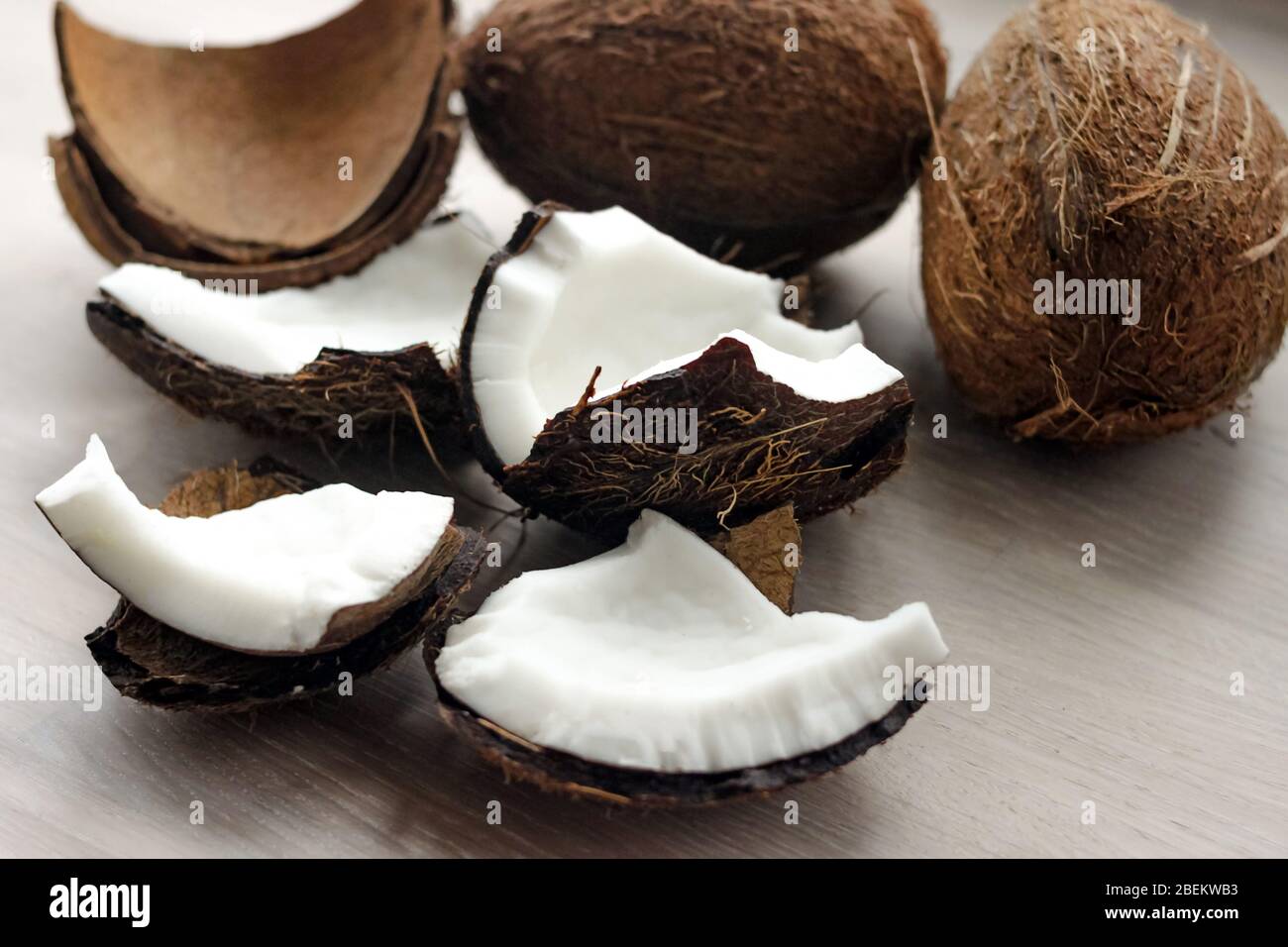 Pieces of broken coconut on white wooden table background. Close up. Selective focus. Copy space Stock Photo