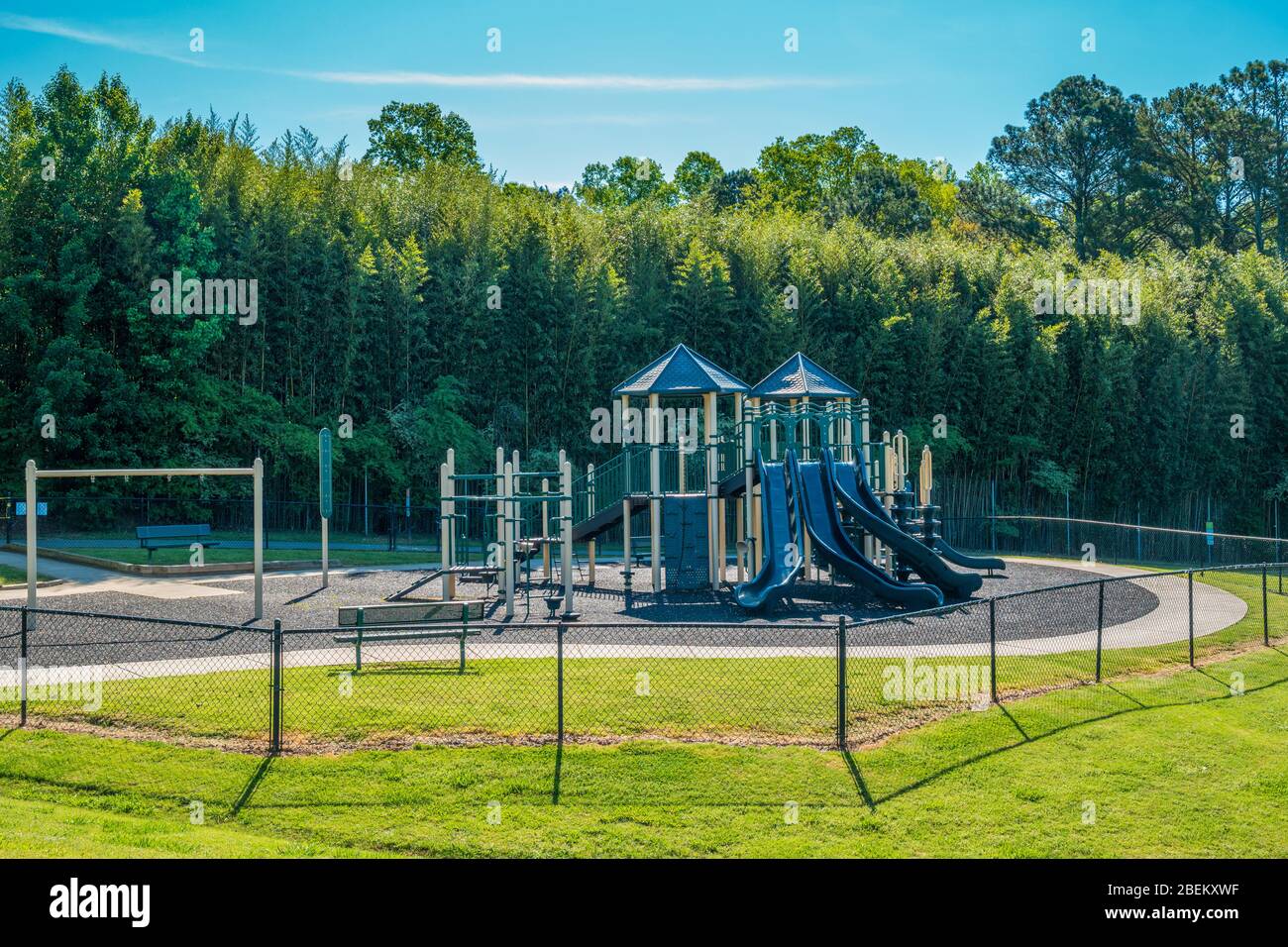 A quiet and empty playground closed and locked up due to the coronavirus pandemic stay at home restrictions on a sunny day in springtime Stock Photo