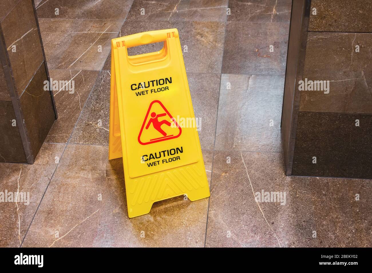 Yellow sign caution wet floor with a falling man in the hallway of the public toilet Stock Photo