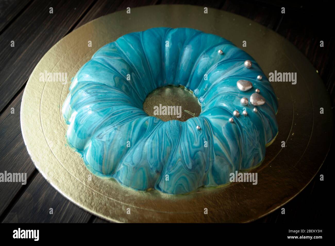 blue berry modern mousse cake, covered with a turquoise mirror glaze with sea effect. Stock Photo