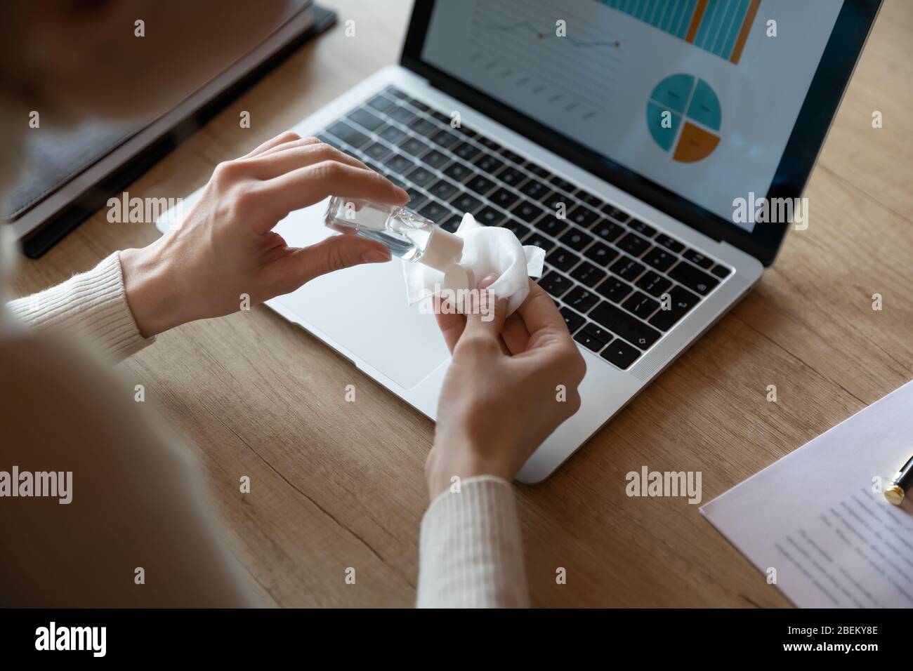 Close up of female employee cleanse computer with sanitizer Stock Photo