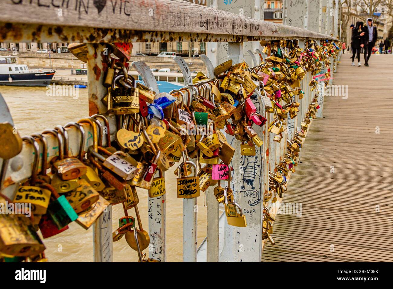 Close up of love padlocks on the Debilly footbridge, with a young couple behind, in Paris, France. February 2020. Stock Photo