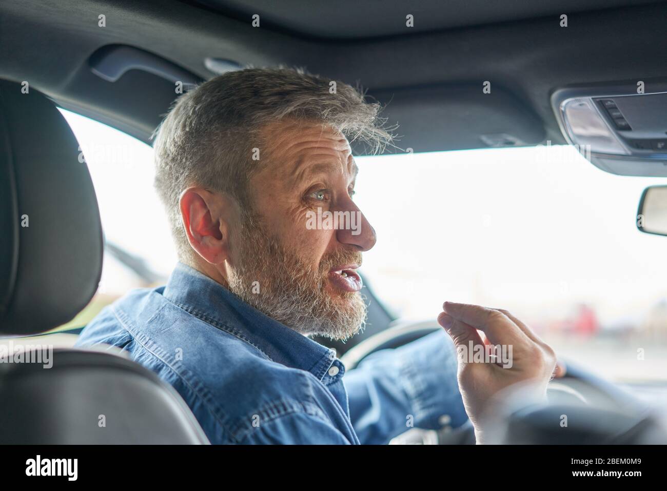 Portrait of a driver talking  in a very angry aggressive way and emphasizing his emotions with his hand Stock Photo