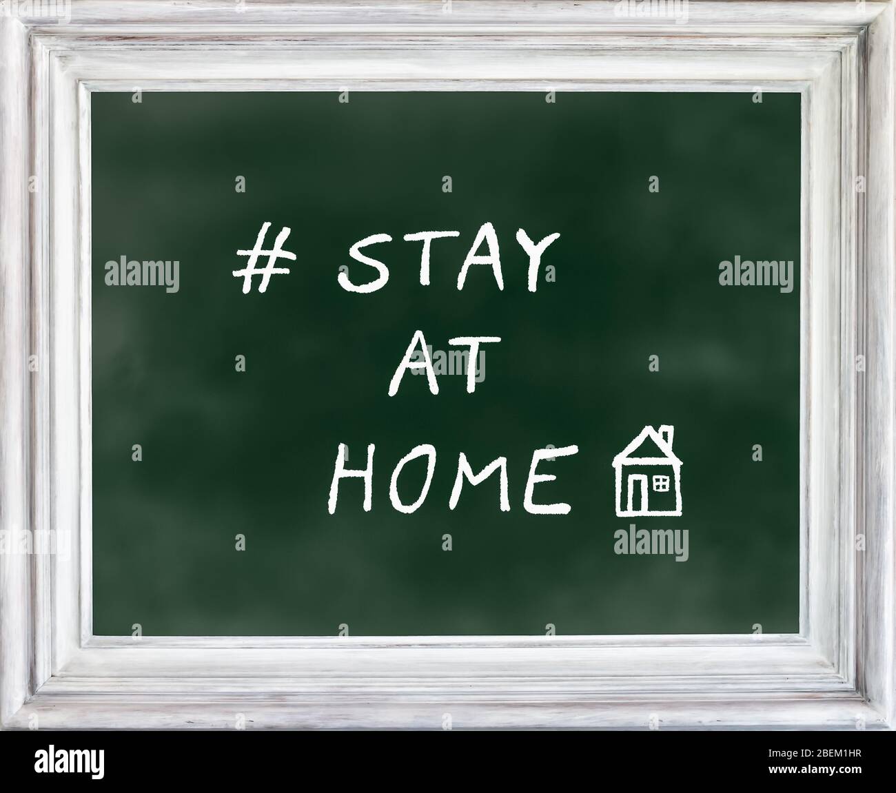 STAY AT HOME written on green chalkboard with drawing of house. Corona virus, covid-19 quarantine concept. Stock Photo