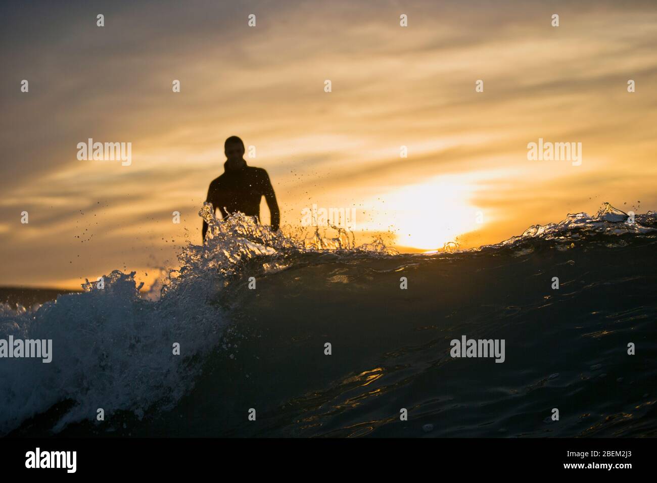 Silhouette of a man standing in the surf at sunset Stock Photo