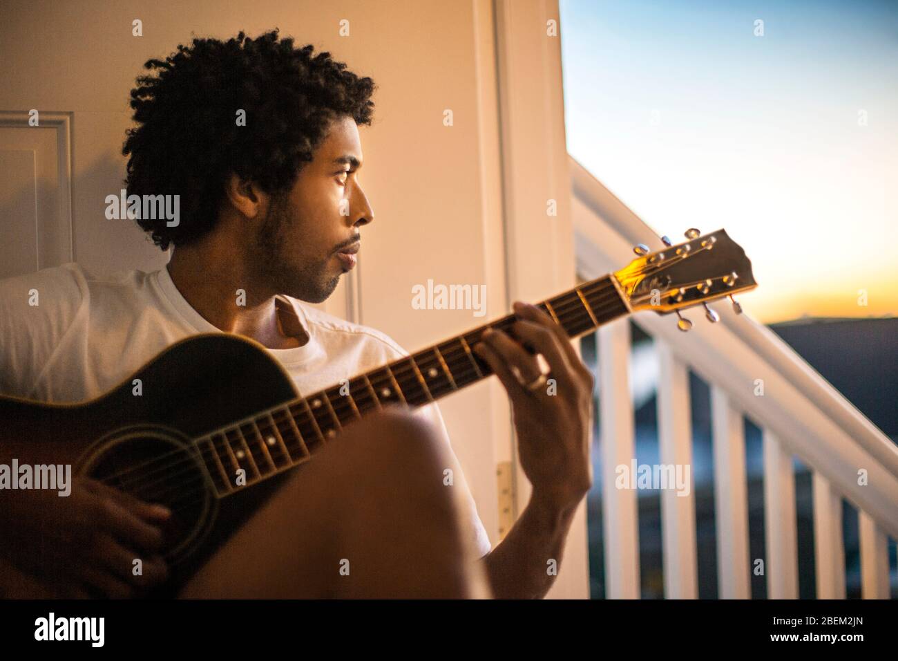 Pensive young man playing an acoustic guitar Stock Photo