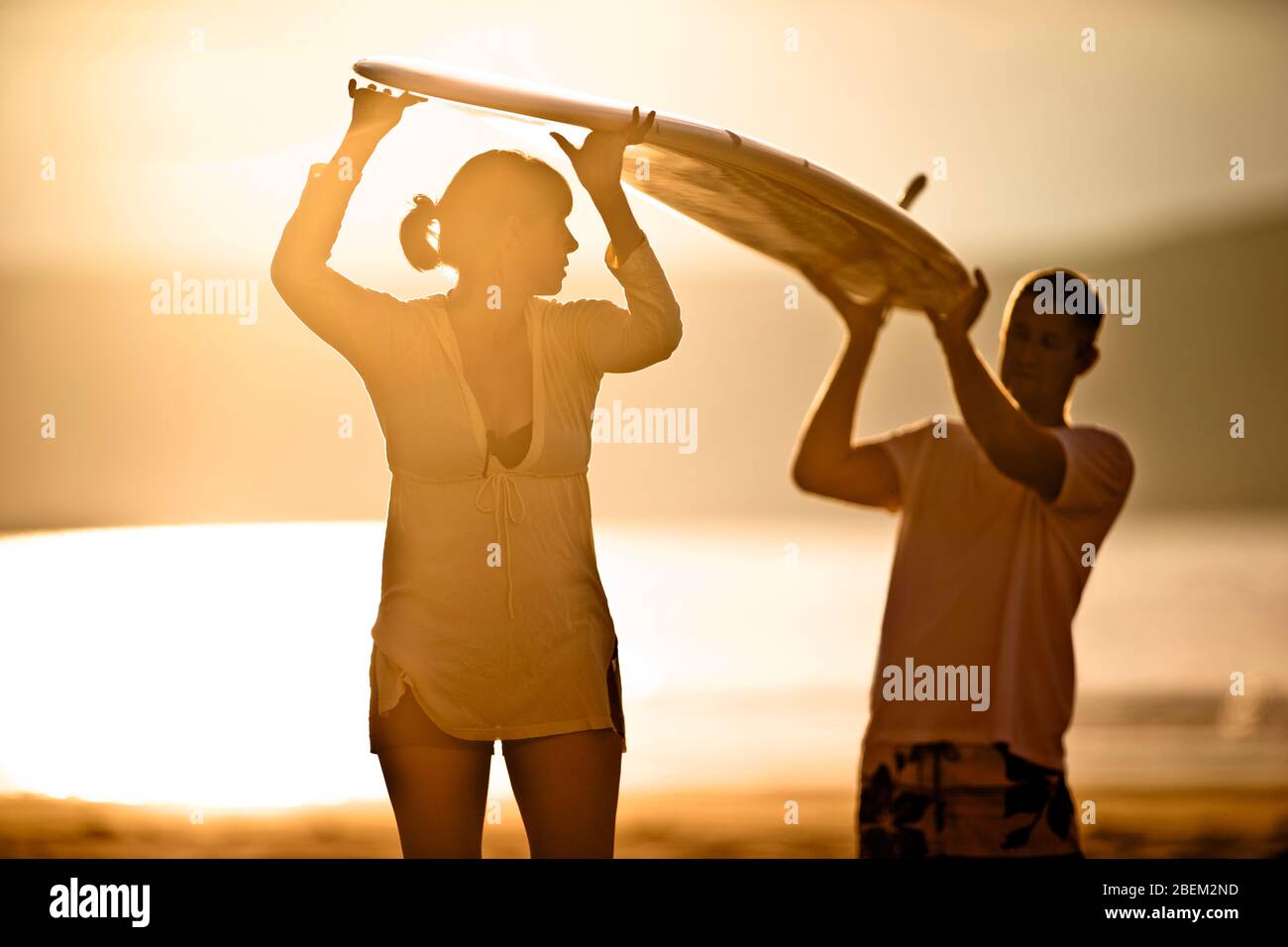 Mid adult couple carrying a surfboard on the beach Stock Photo