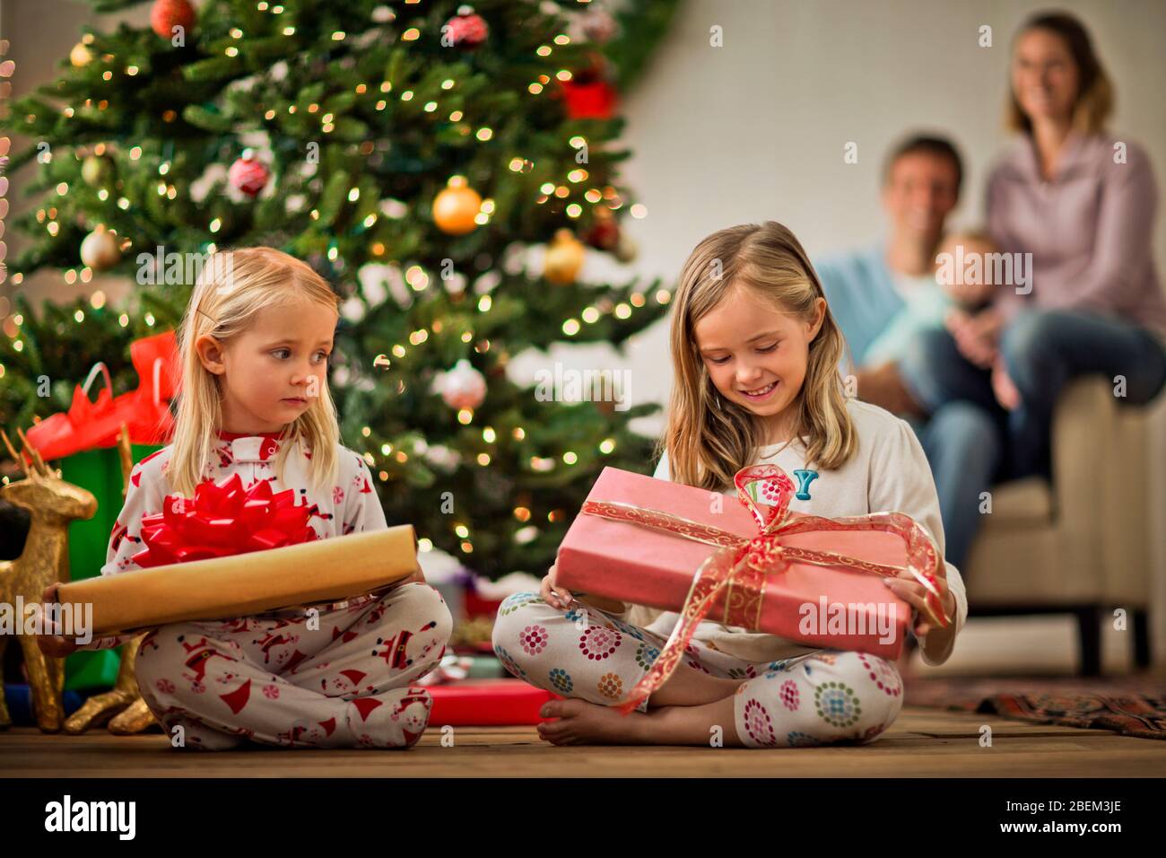 Two young girls opening their Christmas presents Stock Photo