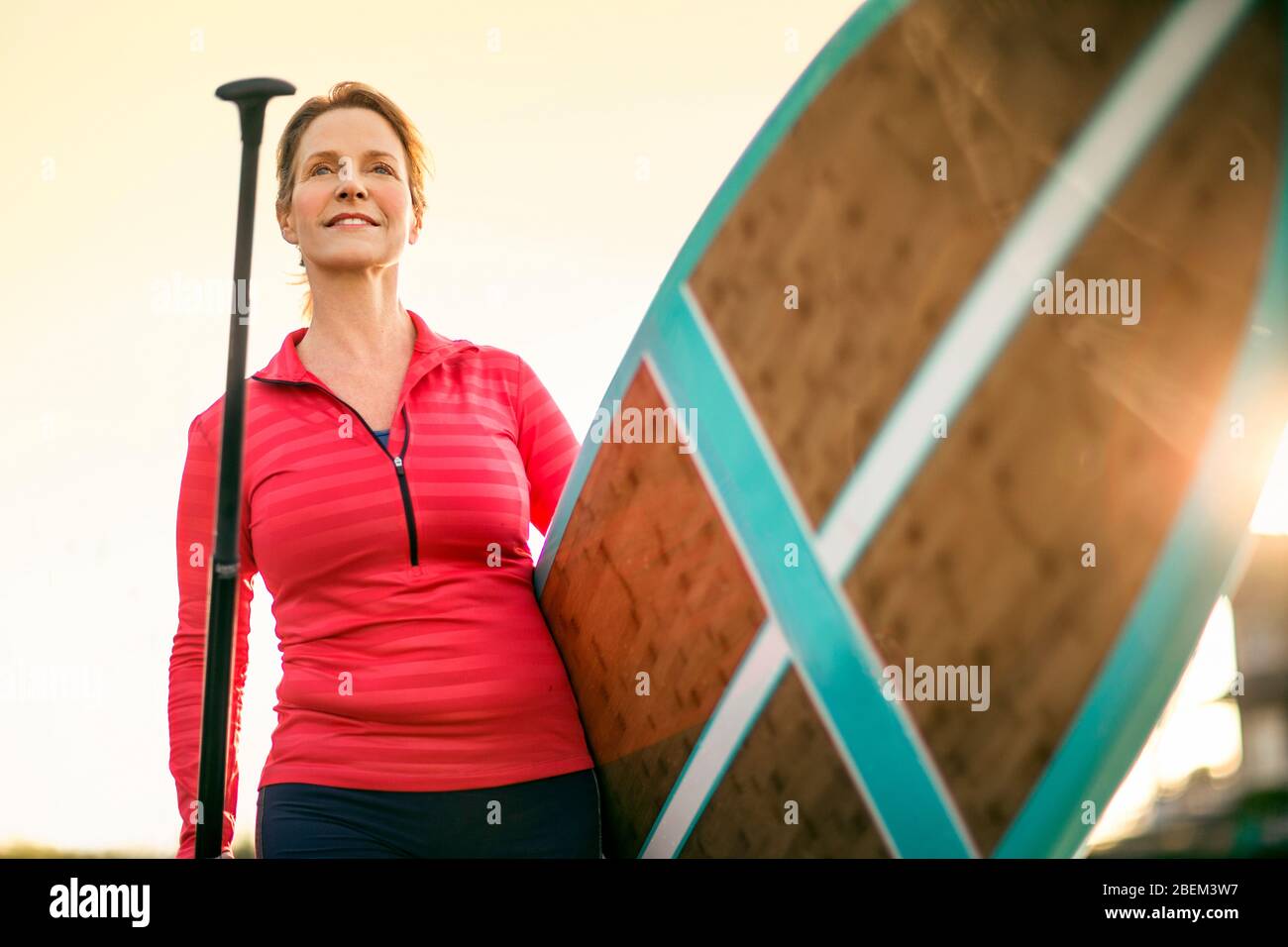 Mid adult woman walking with a paddleboard Stock Photo