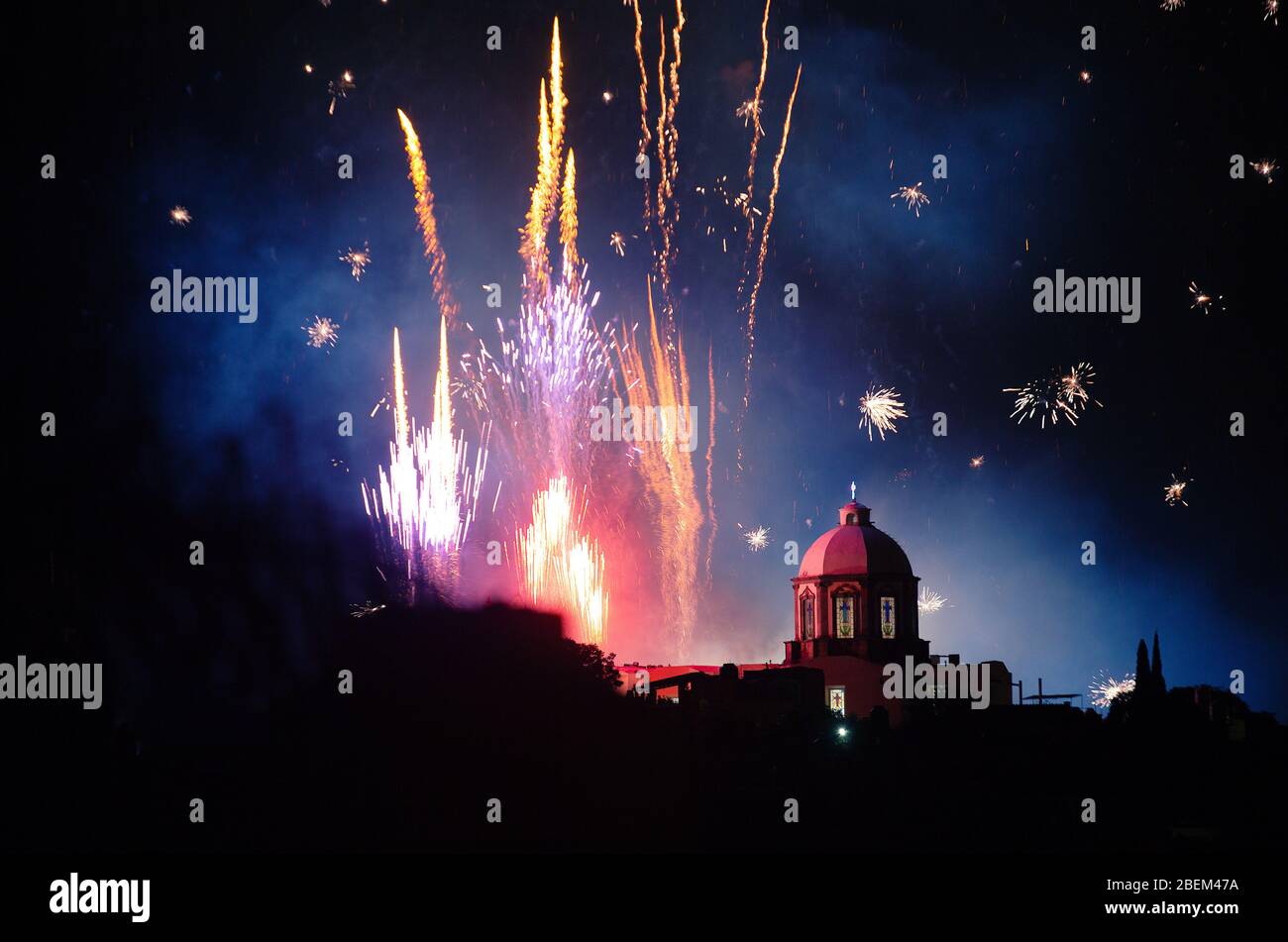 Fireworks erupt over a church in San Miguel de Allende, Mexico, for celebrations around Dia De Los Locos, or the 'Day of the Crazies' festival. Stock Photo