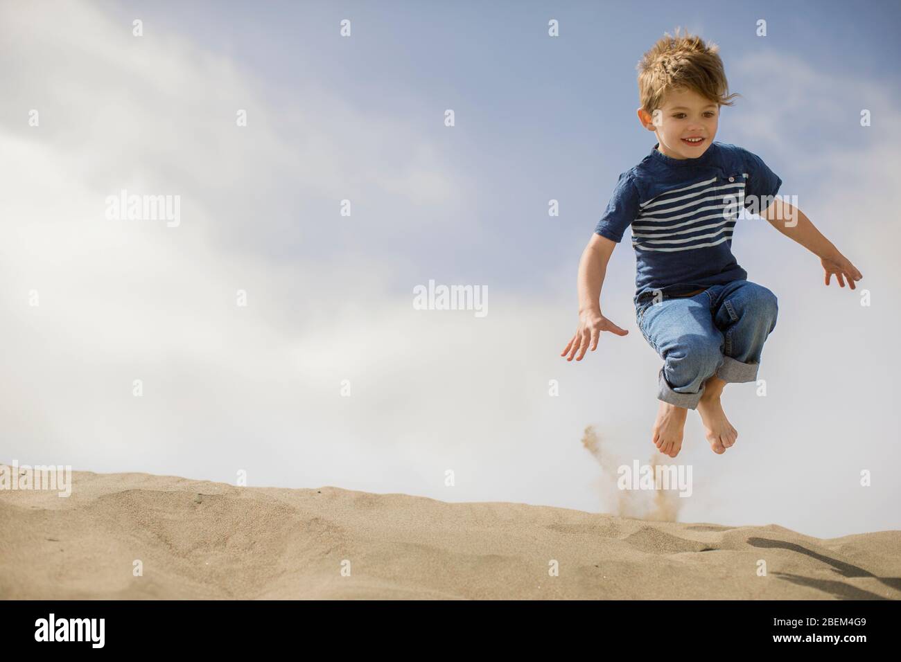 Young boy playing on sand dunes Stock Photo