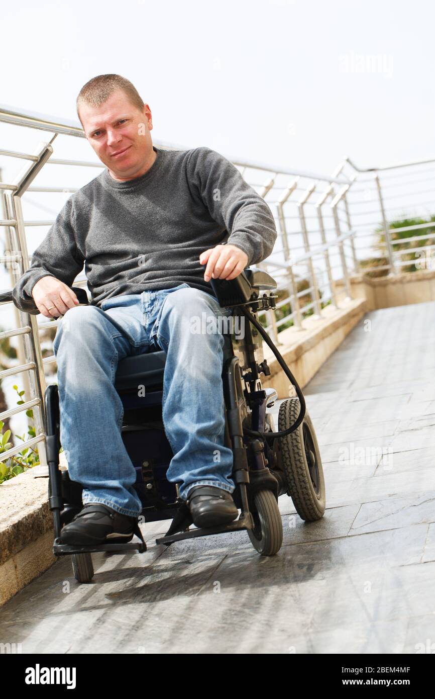 Man in wheelchair sits near the railing Stock Photo