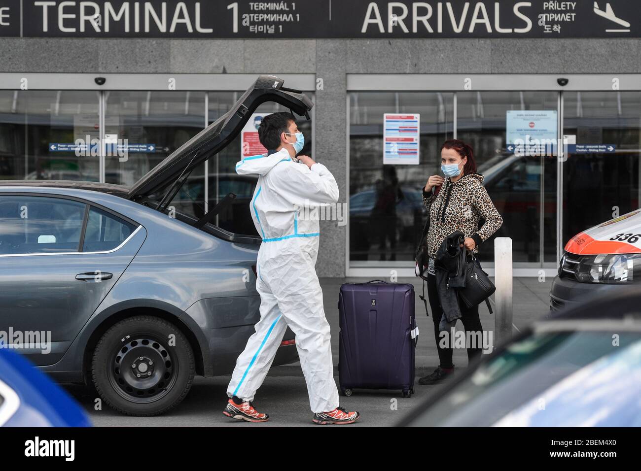 Prague, Czech Republic. 14th Apr, 2020. Passenger wearing face mask loads suitcase to car in front of the Vaclav Havel Airport Prague, Czech Republic, April 14, 2020. An airplane with more than 300 Czech citizens returning from Australia and New Zealand landed in Prague and their evacuation was the last repatriation flight that the Foreign Ministry organised in connection with the new coronavirus pandemic. All Czechs who return from abroad must stay in isolation for two weeks. Credit: Michal Kamaryt/CTK Photo/Alamy Live News Stock Photo