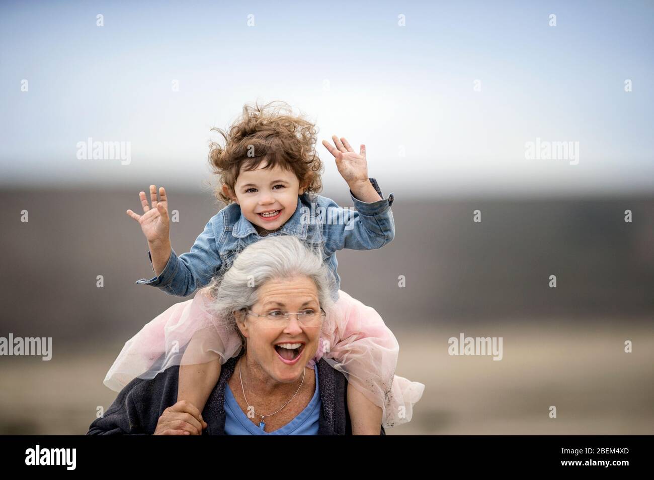 Mature woman carrying her granddaughter on her shoulders Stock Photo