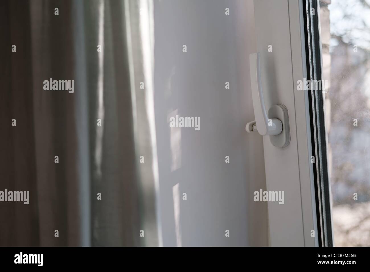 Open white PVC window with a fixing device for ventilation and a