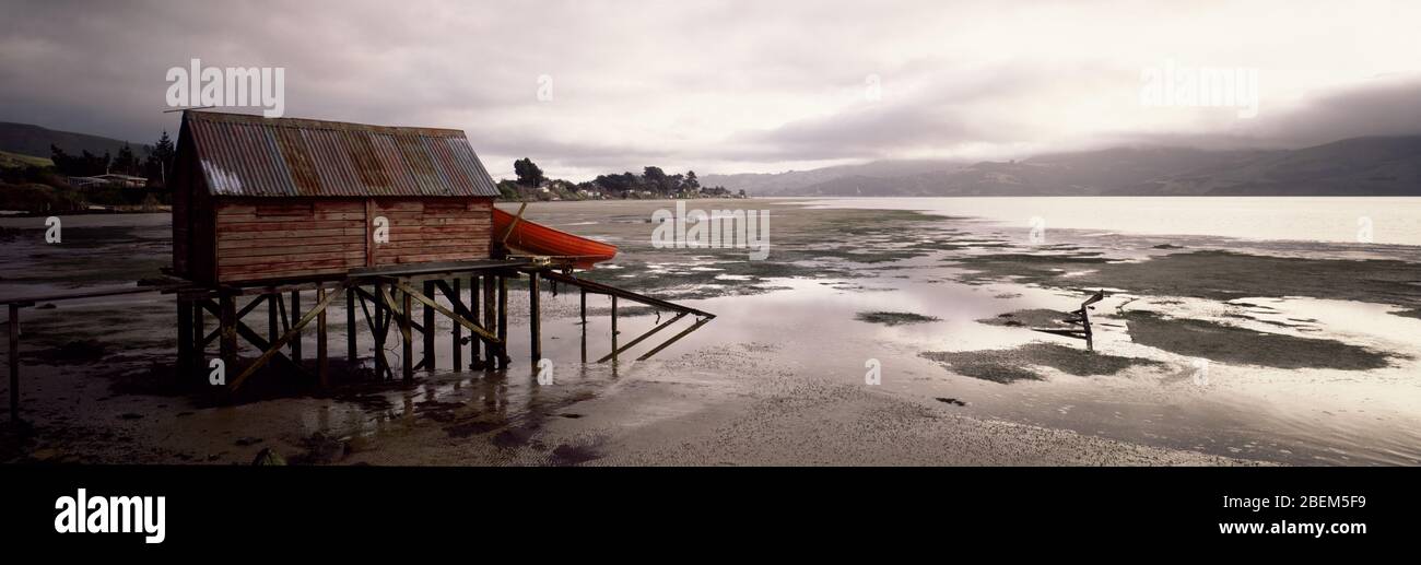 Boat house and dinghy on a costal jetty at low tide. Stock Photo