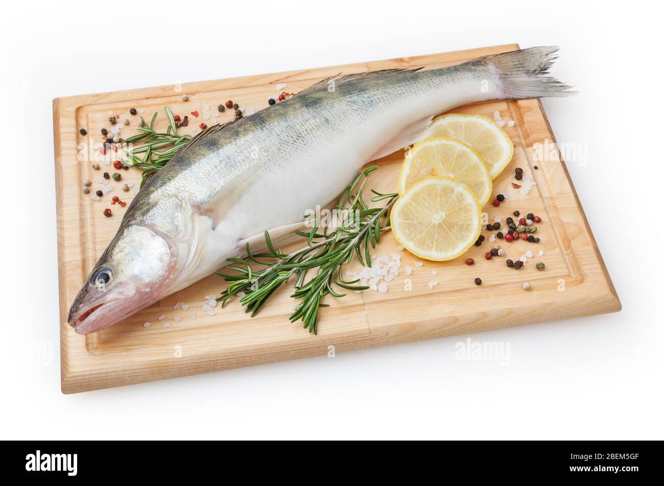 Fresh uncooked pike perch with lemon, rosemary and spice on wooden board isolated on white background with clipping path Stock Photo