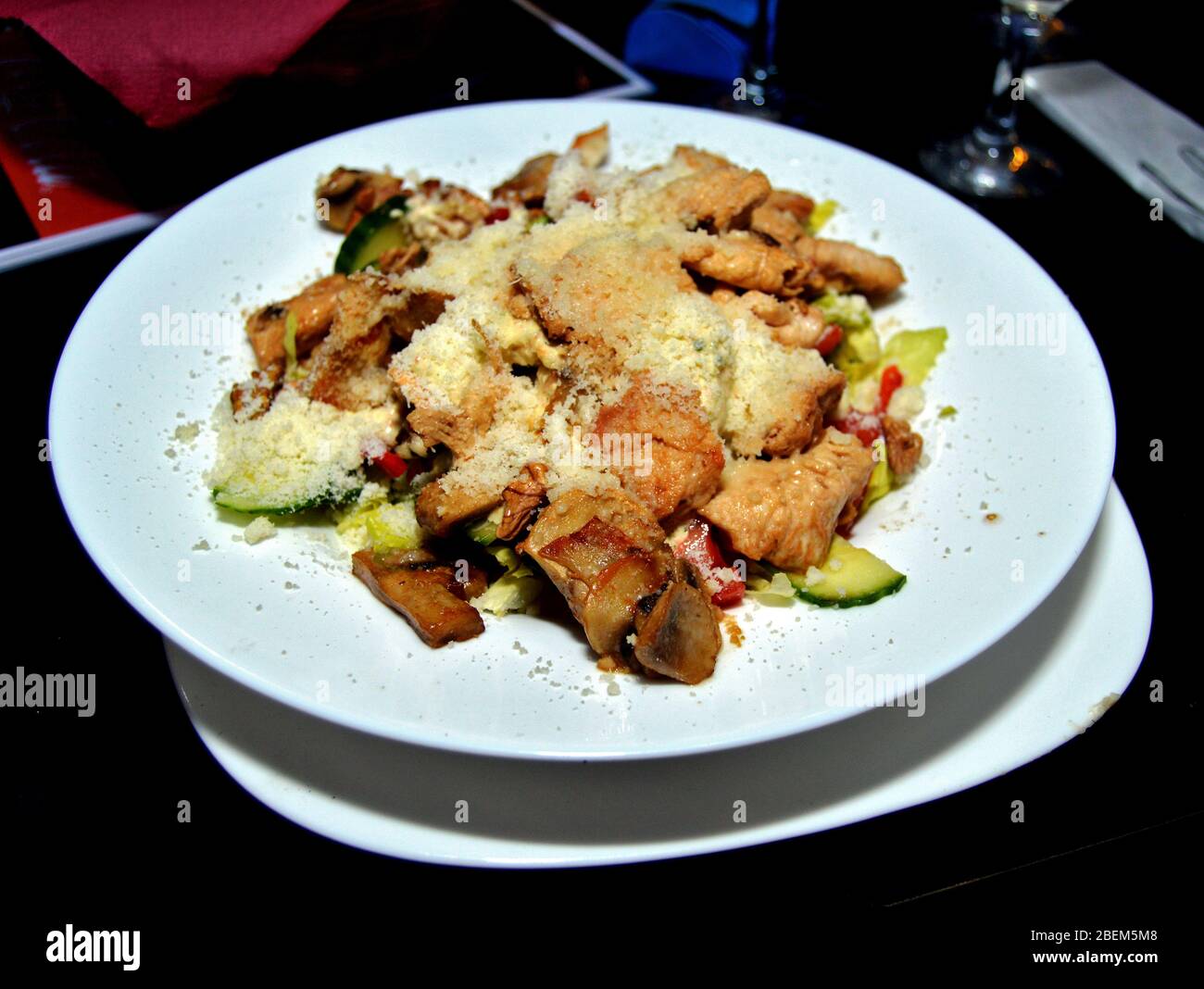 Serving of healthy salad with vegetables, chicken bits and sprinkled with parmesan cheese, a delicious dish great for diets made with organic ingredie Stock Photo