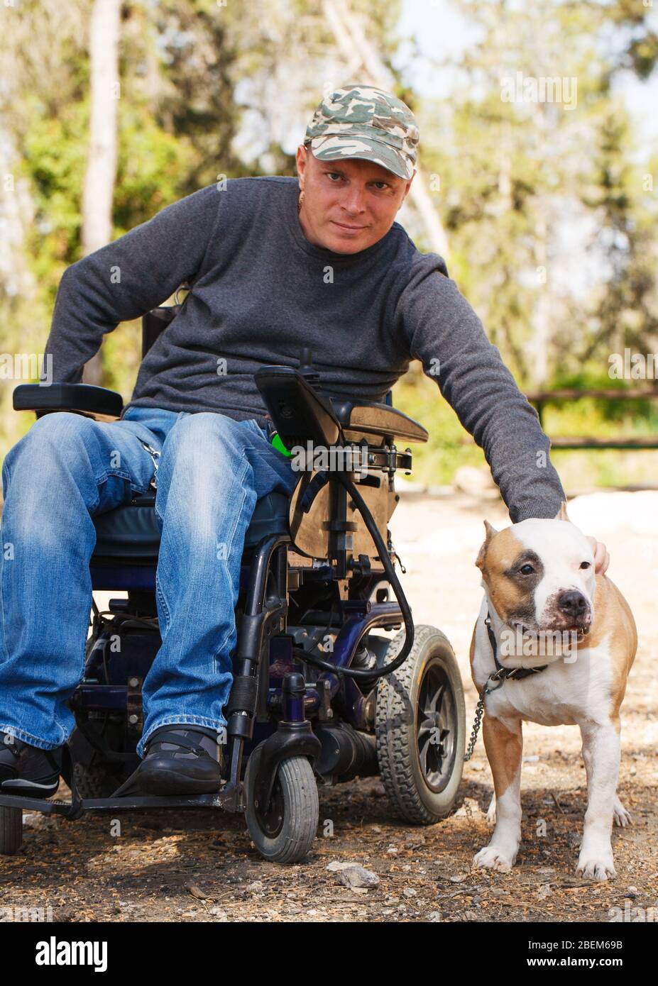 Young man in a wheelchair with his faithful dog walk in the park. Stock Photo