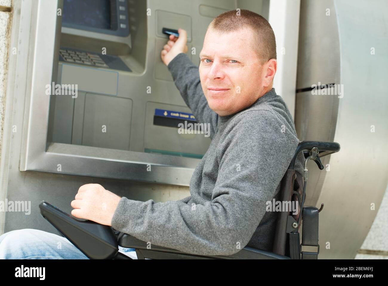 Disabled Man put his credit card at the ATM. Stock Photo