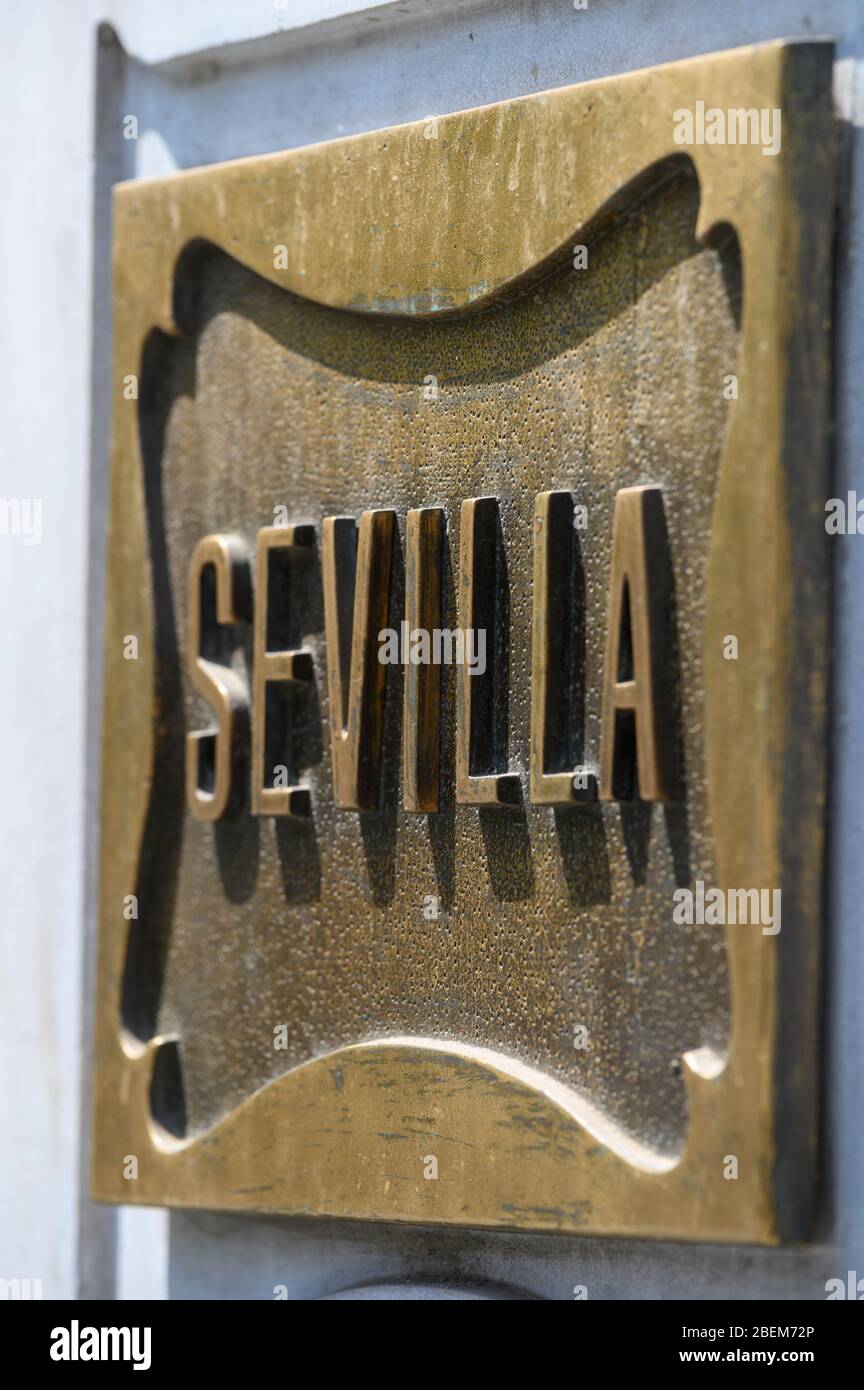 A bronze plaque spelling the word Sevilla attached to an old building