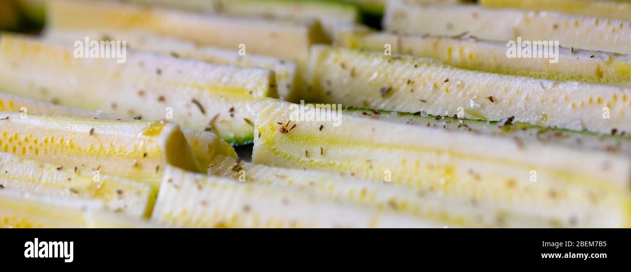 Panorama banner of fresh seasoned zucchini slices or courgettes ready for oven roasting sprinkled with aromatic herbs in a low angle full frame view Stock Photo