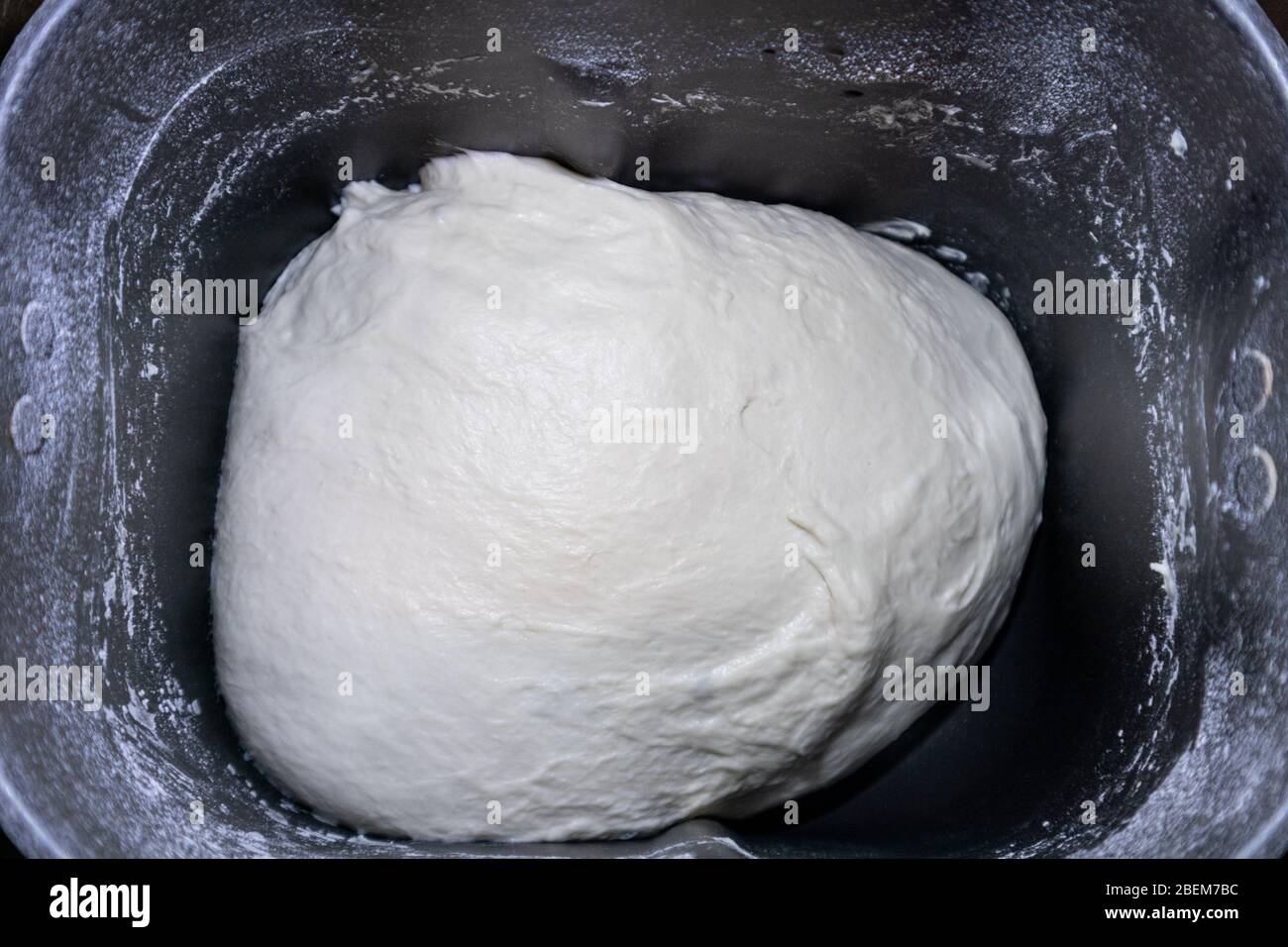 Bread dough in bread maker machine dispenser. Just mixed ready to rise fresh white home made bread pizza pastry duff cooking process close-up on dark Stock Photo