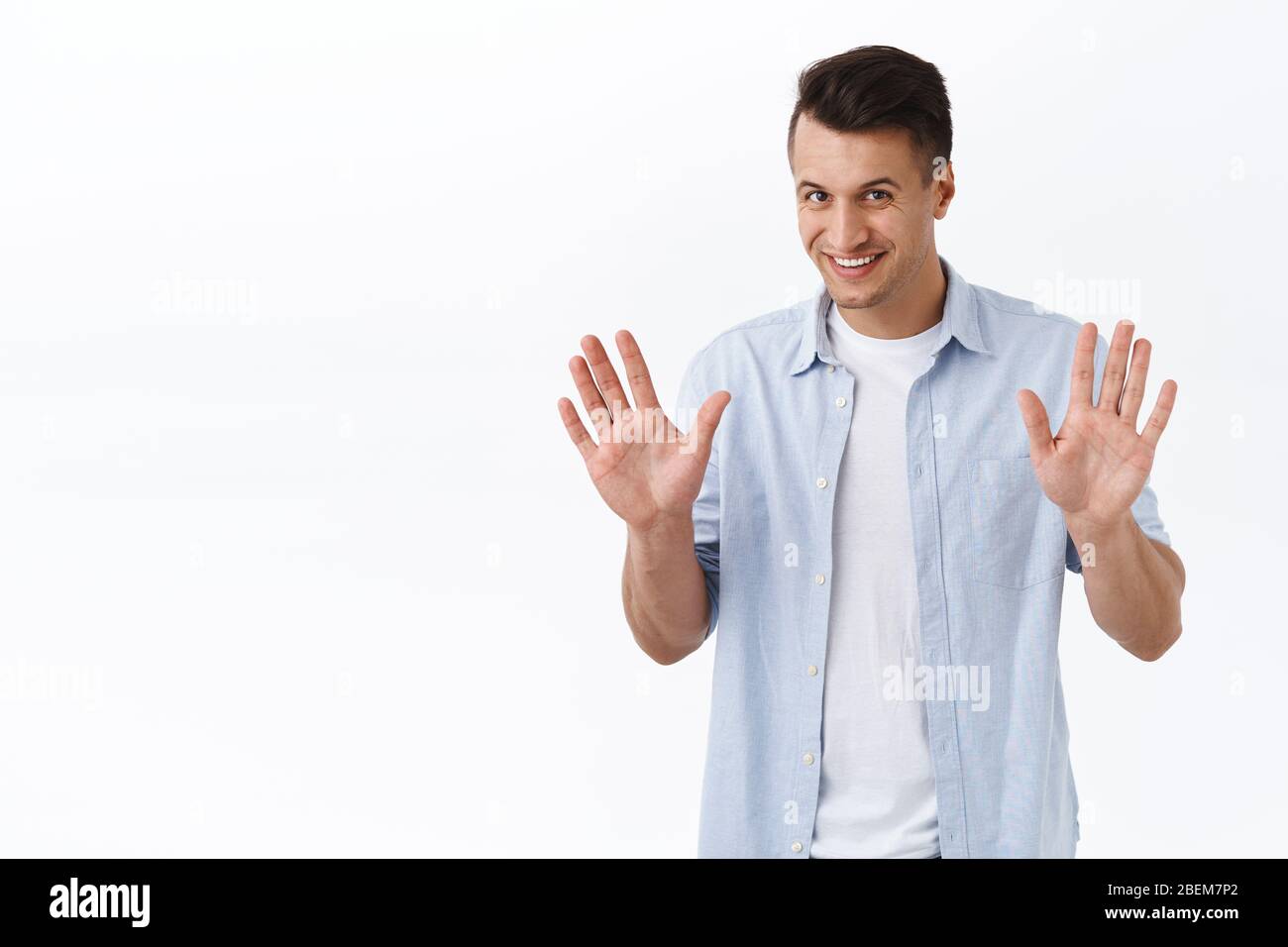 Sorry my bad, forget about it. Portrait of friendly-looking smiling young man apologizing for interruption, raising hands in surrender excusing Stock Photo