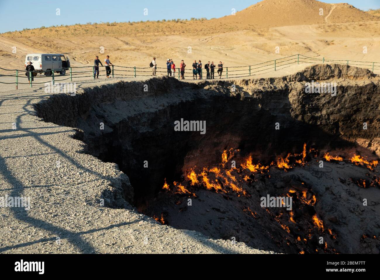 People standing by the edge of The Darvasa Crater, also known as the Doorway to Hell, the flaming gas crater in Darvaza (Darvasa), Turkmenistan Stock Photo