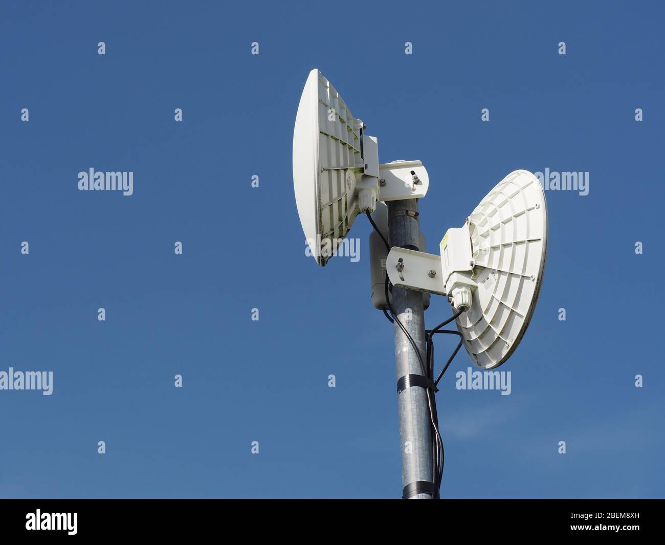 Aerials/router of rural broadband wireless Internet service. Dishes for backhaul to masts on the network backbone, upright aerials for local premises. Stock Photo