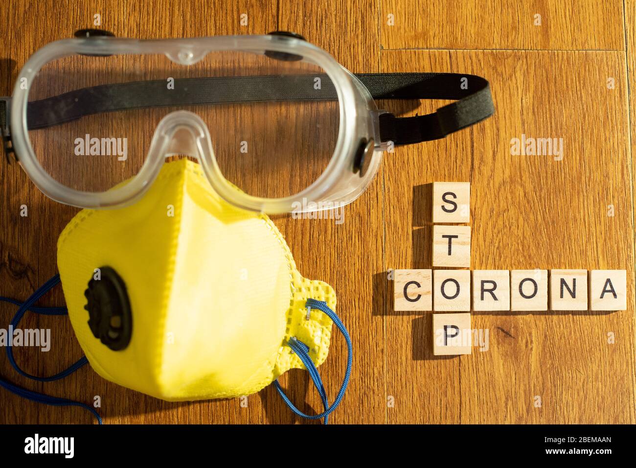 Protective eyewear and yellow mask with outlet valve with wooden blocks  spelling out stop corona on a wood floor Stock Photo - Alamy