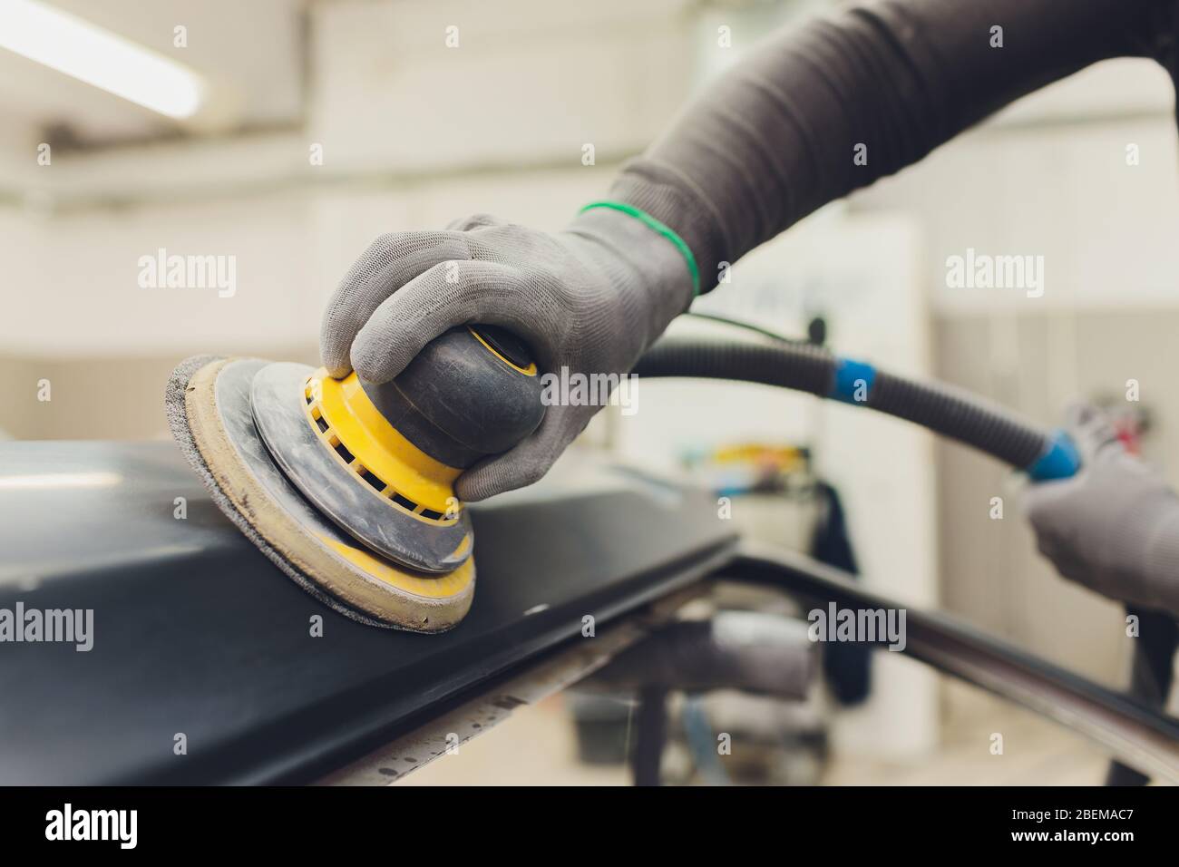 Auto mechanic preparing the car for paint job by applying polish with ...