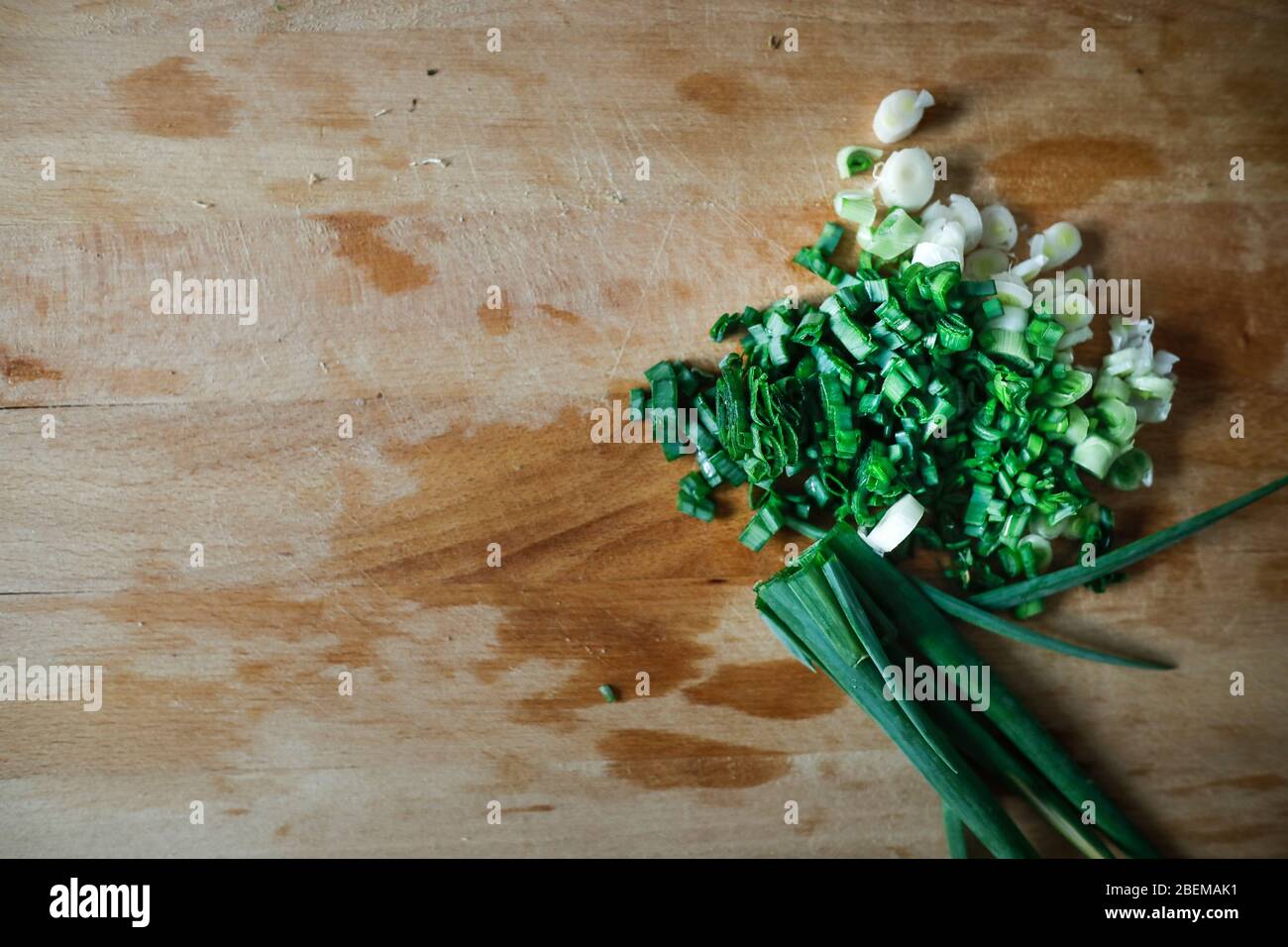 Shallow depth of field (selective focus) image with chopped spring onions on a wooden cutter. Stock Photo